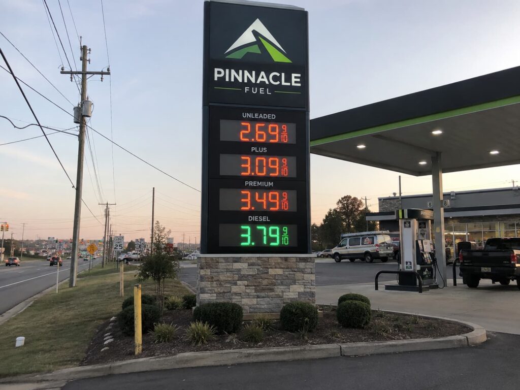 Custom gas station pylon sign with LED price display near roadside