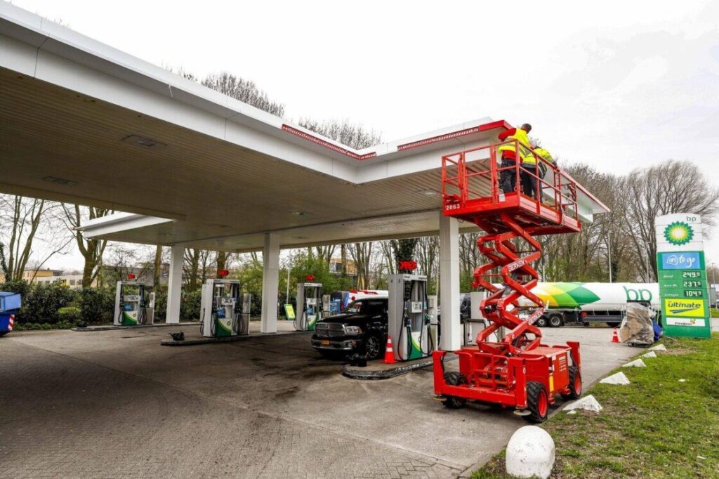 Workers upgrading fascia on an existing BP gas station canopy