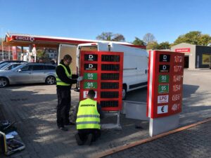Technicians installing LED price change signs at a gas station