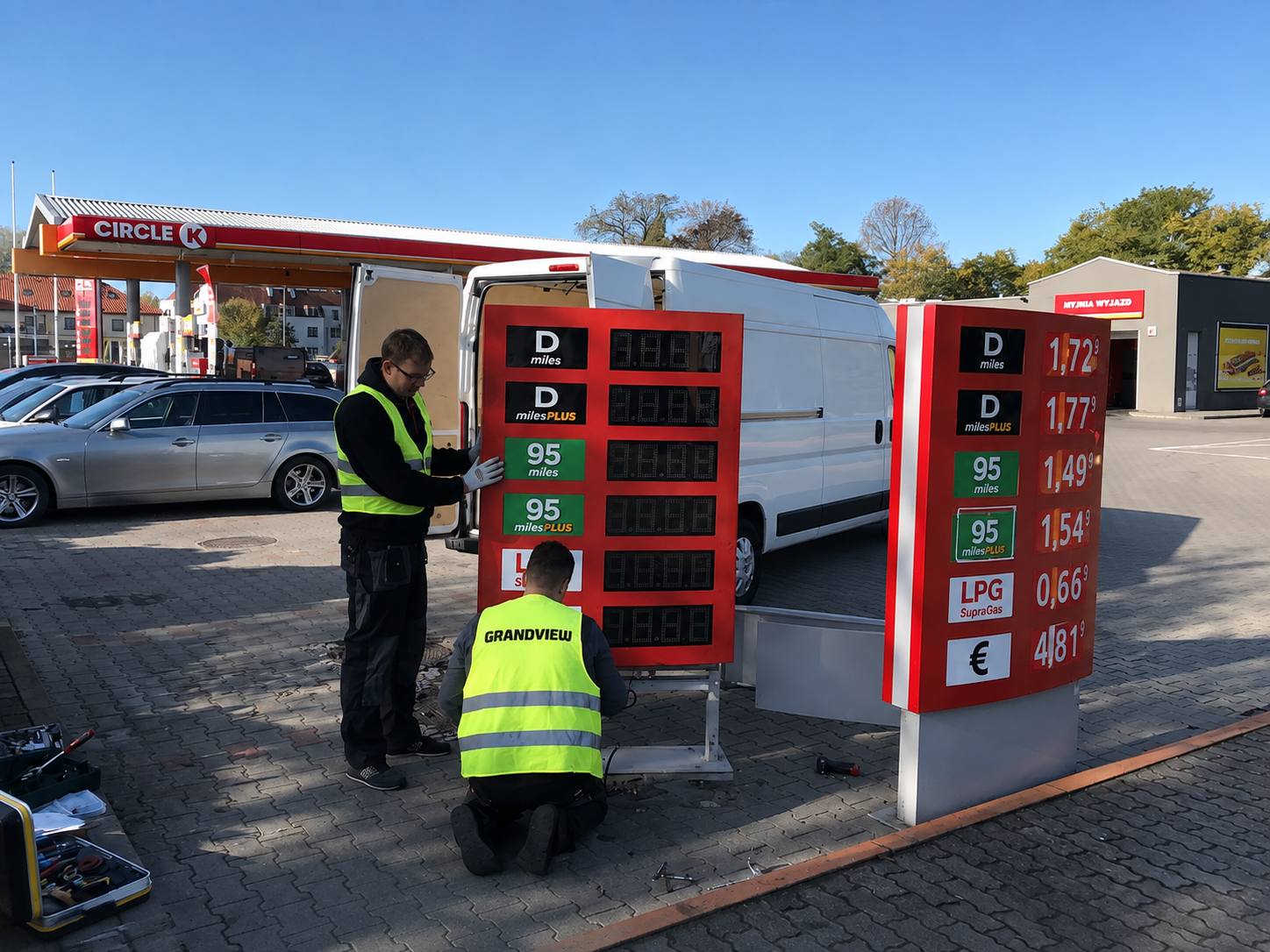 Technicians installing LED price change signs at a gas station